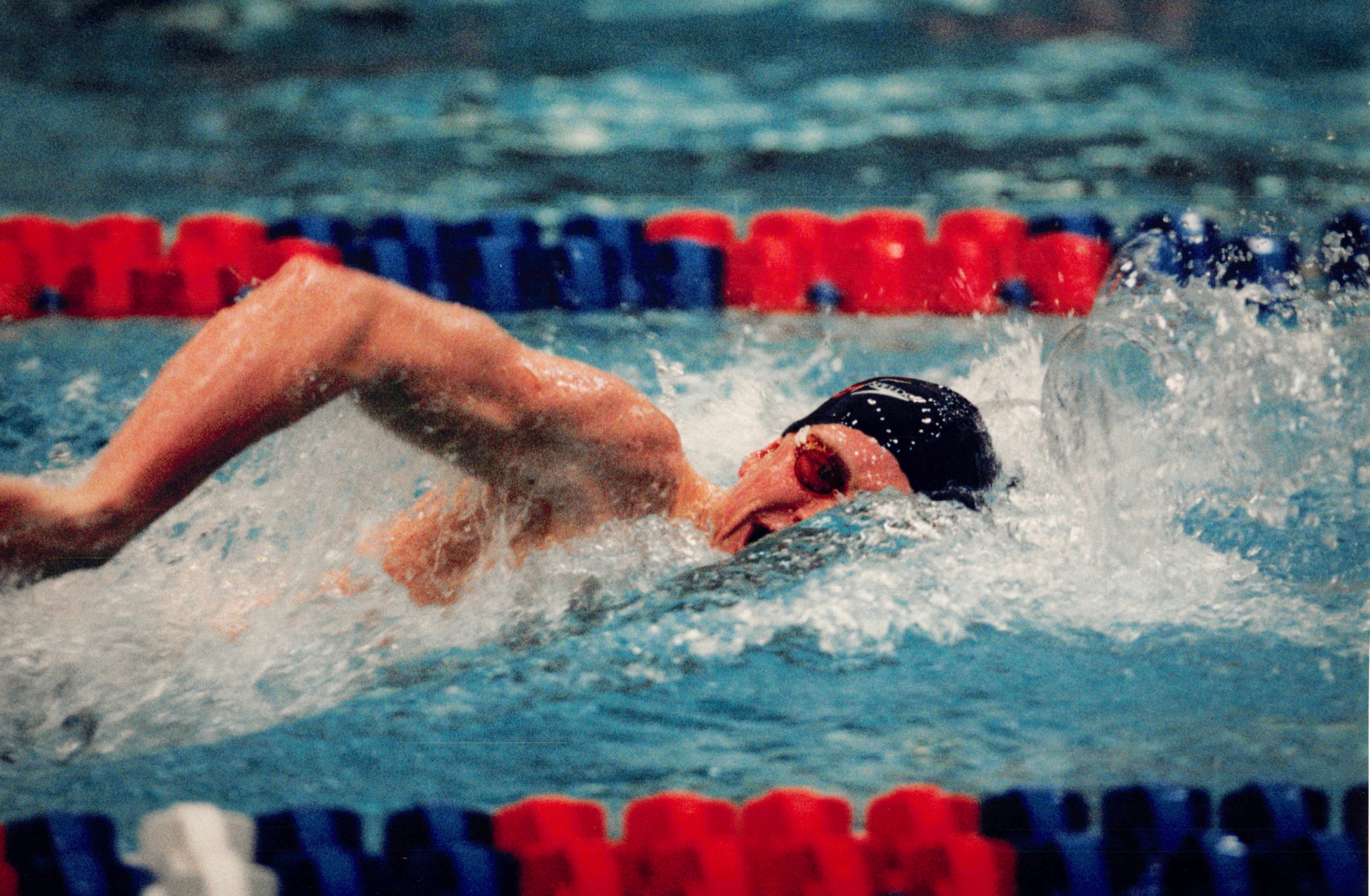 Adam mid-freestyle stroke in a race, navy cap and goggles